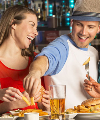A woman laughs while a man to her right steals a French fry offer her plate at 99 Hops House at Hollywood Casino Joliet.