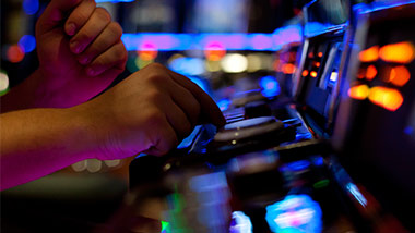 Picture of a player's hands pushing the play button on a slot machine.